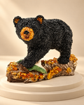A walking bear with a dark textured body, honey-toned muzzle and ears, on a woodland-style base with a small green fish detail.