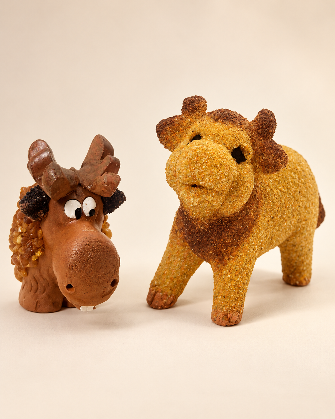 Two decorative designs shown together: a golden-toned standing lion with a brown mane, and a playful moose-head design with broad antlers. Individual pricing and whether sold separately remain to be confirmed.
